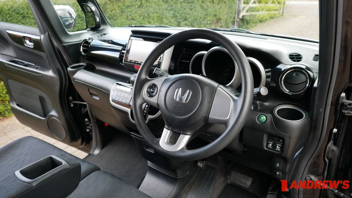 Picture showing the steering wheel, arm rest and 90 degree door opening of a Honda N-Box Custom